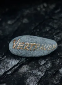 Vertrauen in goldener Schrift auf Stein